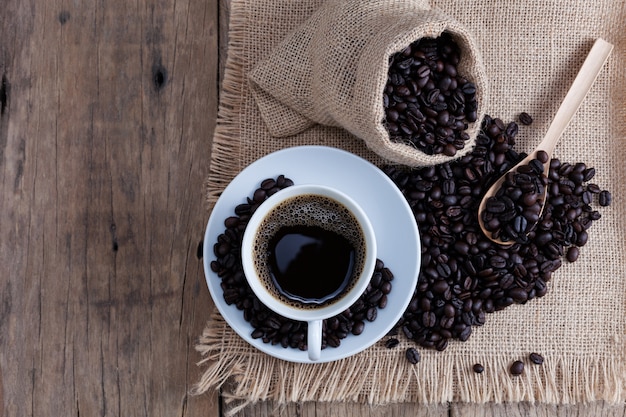 Kaffeetasse und Kaffeebohnen auf altem hölzernem Plankenhintergrund.