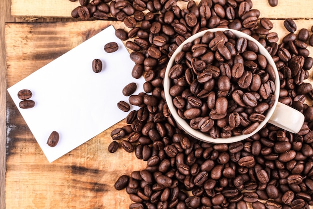 Kaffeetasse und Kaffeebohnen auf hölzernem Hintergrund. mit weißer Note