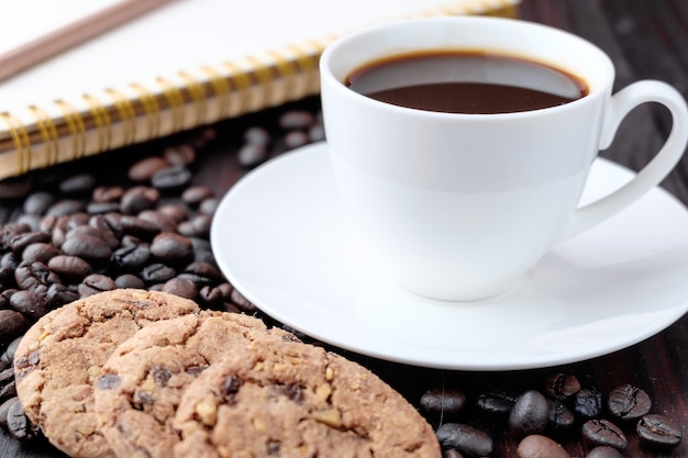 Foto kaffeetasse und kaffeebohnen auf hölzernem hintergrund