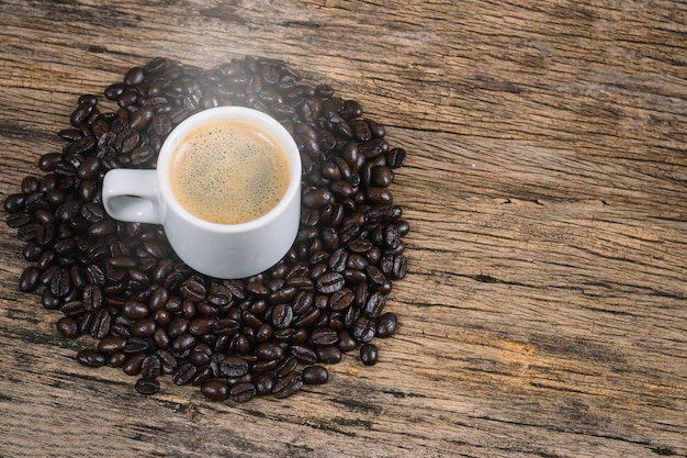 Kaffeetasse und Kaffeebohnen in einem Sack auf einem Holzboden geröstet.