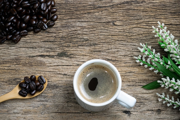 Kaffeetasse und Kaffeebohnen in einem Sack auf einem Holzboden geröstet.