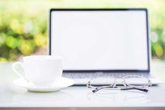 Kaffeetasse und Laptop im Büro mit Brille