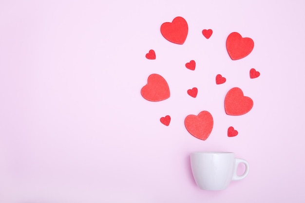 Kaffeetasse und rote Holzherzen auf rosa Hintergrund Das Konzept der Valentine39s Day Love Dating und Hochzeit Symbol eines romantischen Geschenks oder Heiratsantrags Kopieren Sie Platz Minimalismus
