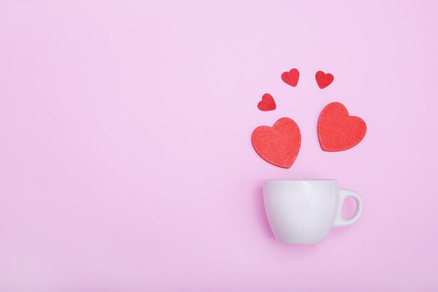 Kaffeetasse und rote Holzherzen auf rosafarbenem Hintergrund Das Konzept von Valentine39s Day Love Dating und Hochzeit Symbol für ein romantisches Geschenk oder einen Heiratsantrag Kopieren Sie Platz Minimalismus