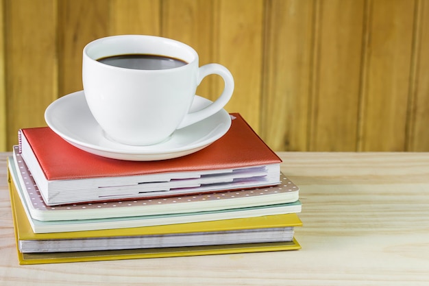 Kaffeetasse und Schreibwaren auf Holztisch-Büroschreibtischkonzept