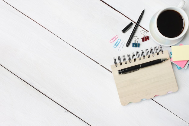 Kaffeetasse und stift, notizbuch auf weißem hölzernem schreibtisch und haben kopienraum.