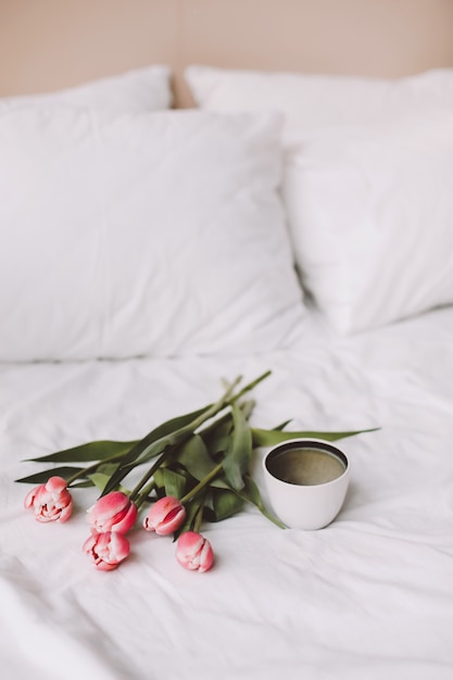 Kaffeetasse und Tulpen im Bett