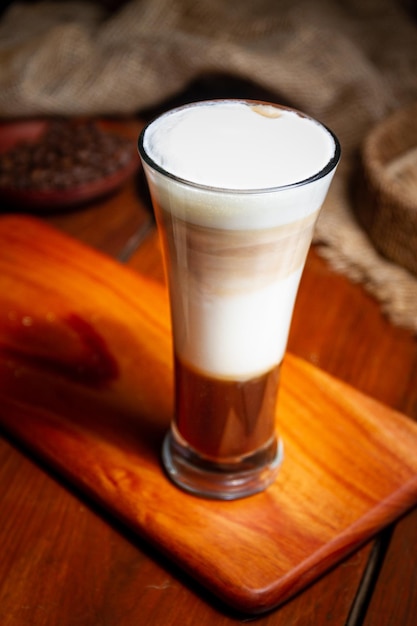 Kaffeetassen Milchbohnen und gemahlener Kaffee im Glas auf Holzhintergrund Hochwertiges Foto