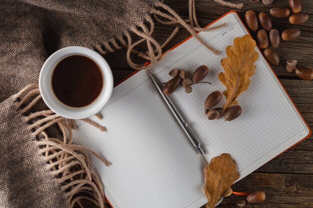 Kaffeetassen, Notizbuch und Herbstlaub