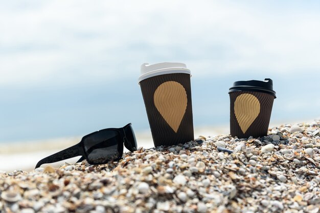 Kaffeetassen und Gläser liegen im Sand am Meer