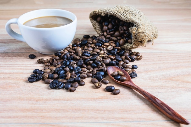 Kaffeetassen und Röstkaffeebohnen auf einem Holztisch