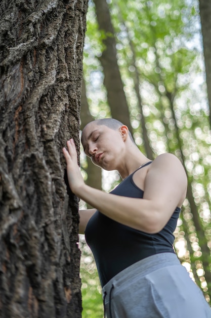 kahles Mädchen meditiert stehend am Baum