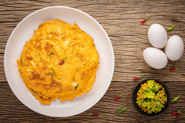 Kai Jeaw Dok Ka Jon Moo Sub, comida tailandesa, tortilla con flores de enredadera de prímula, carne de cerdo picada y chile sobre fondo de textura de madera rústica, vista superior