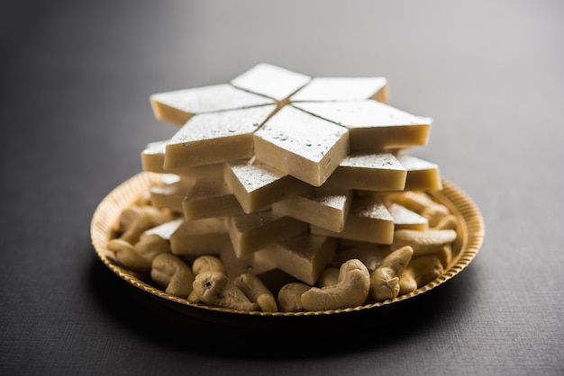 Kaju Katli es un dulce indio con forma de diamante elaborado con azúcar de anacardo y mava, servido en un plato sobre una superficie de mal humor. enfoque selectivo