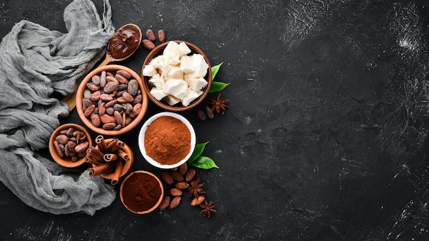 Kakaobohnen, Schokolade, Kakaobutter und Kakaopulver auf schwarzem Hintergrund Draufsicht Freier Kopierbereich