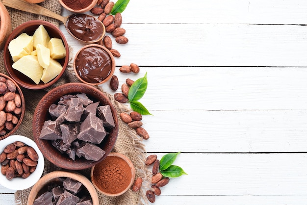 Kakaobohnen, Schokolade, Kakaobutter und Kakaopulver auf weißem Holzhintergrund Draufsicht Freier Kopierraum