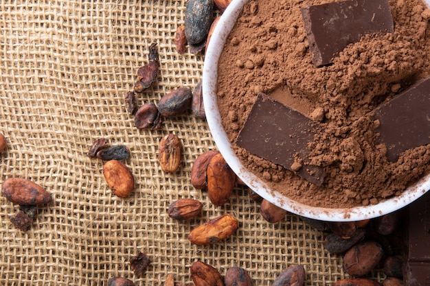 Foto kakaopulver mit schokoladenstücken auf rohen kakaobohnen.