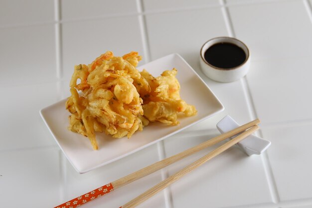 Kakiage tempura, legumes fritos servidos em prato branco.