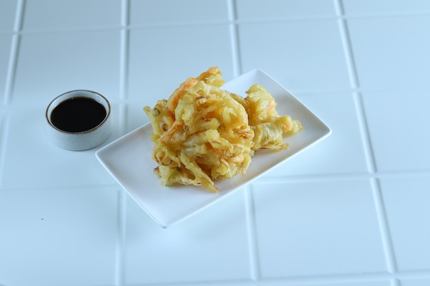 Kakiage tempura, legumes fritos servidos em prato branco.