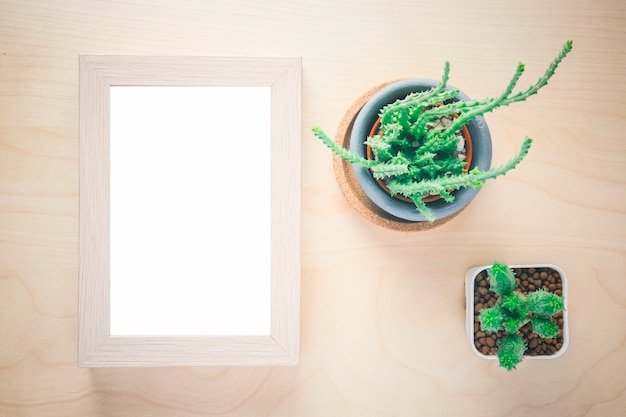 Kaktus im Topf und im leeren Fotorahmen auf Holztisch