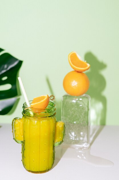 Kaktusförmiges Glas mit Orangensaft mit Fruchtdekoration auf Eisblock. Platz kopieren.