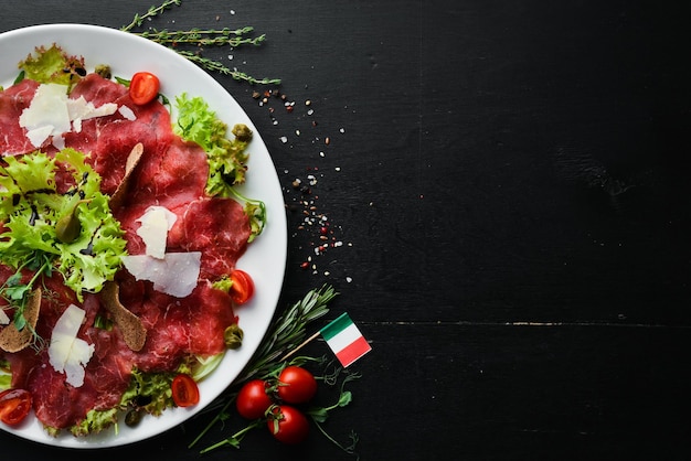 Kalbscarpaccio Kalbfleisch mit Kapern und Parmesan Draufsicht Freier Kopierplatz