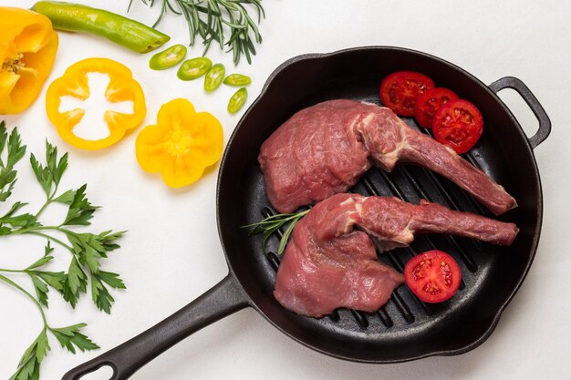 Kalbsfleisch mit Knochen in einer Pfanne mit farbig gehackten Paprikaschoten.