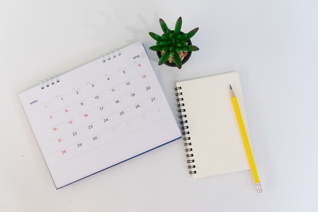 Kalender April 2019 mit Notizbuch, Stift und Anlage am Schreibtisch mit Draufsichtkonzept