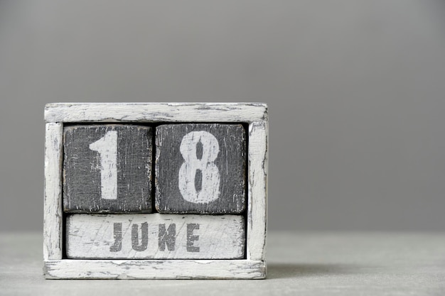Kalender für den 18. Juni aus Holzwürfeln auf grauem Hintergrund mit einem leeren Platz für Ihren Text