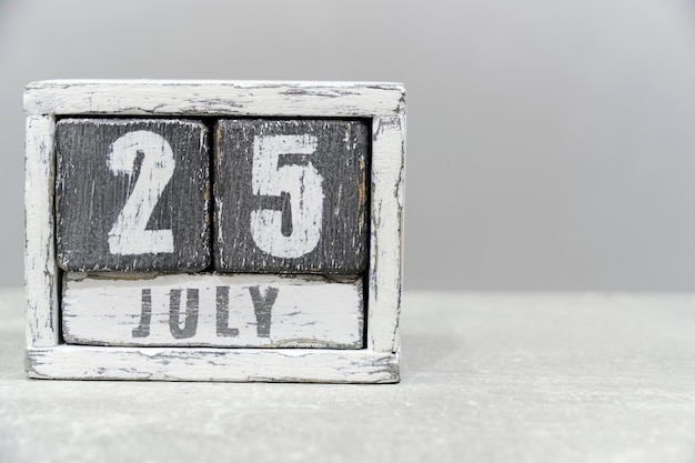 Kalender für den 25. Juli aus Holzwürfeln auf grauem Hintergrund mit einem leeren Platz für Ihren Text