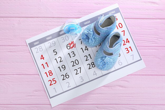 Kalender mit Babyschuhe auf Holzuntergrund