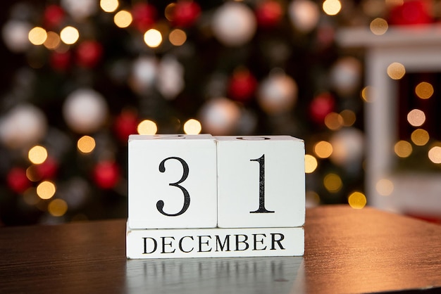 Kalender mit dem Datum 31. Dezember auf dem Hintergrund von Kerzen und Weihnachtsdekor in Rot