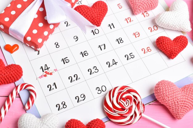 Kalender mit dem Zeichen des Valentinstags. Ein bunter Lutscher und eine Geschenkbox oben auf dem Februar-Kalender. Platz kopieren. Flache Lage, Ansicht von oben