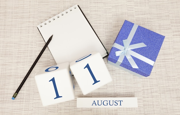 Kalender mit trendigen blauen Text und Zahlen für den 11. August und ein Geschenk in einer Box.