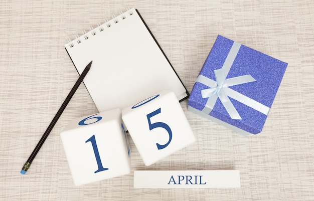 Foto kalender mit trendigen blauen text und zahlen für den 15. april und ein geschenk in einer box.