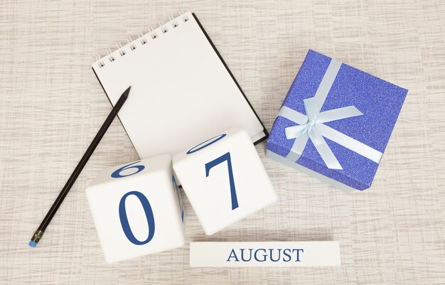 Kalender mit trendigen blauen Text und Zahlen für den 7. August und ein Geschenk in einer Box.