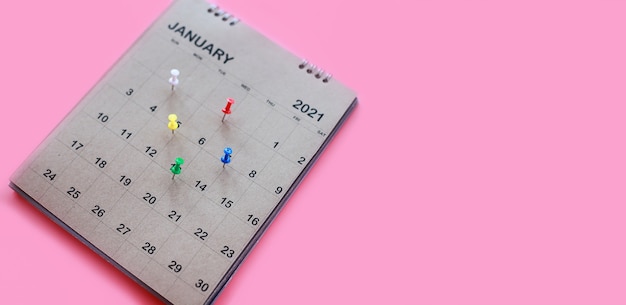 Kalender und Terminplaner mit einem Pin auf rosa Hintergrund.