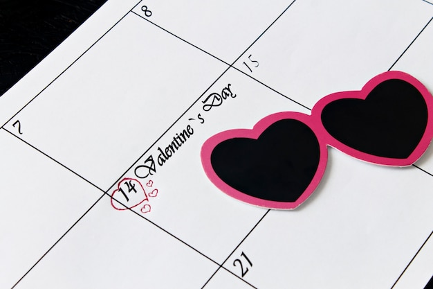 Foto kalenderseite mit herzen am 14. februar, valentinstag auf einem schwarzen hintergrund.