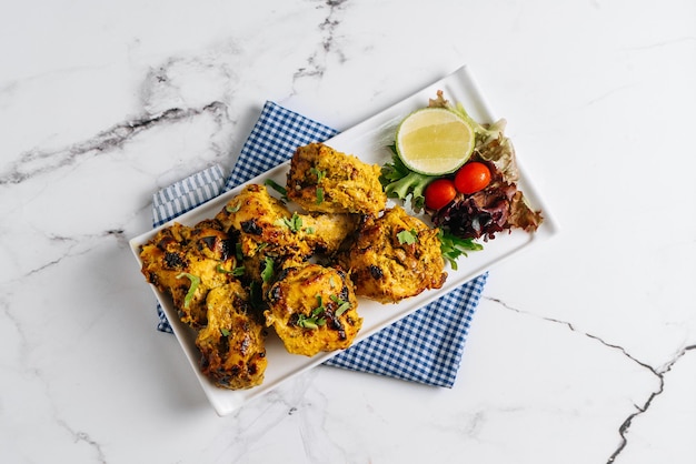 Kali Mirchi o kebab de ternera a la pimienta negra con lima en un plato aislado en la vista lateral de la servilleta sobre fondo gris