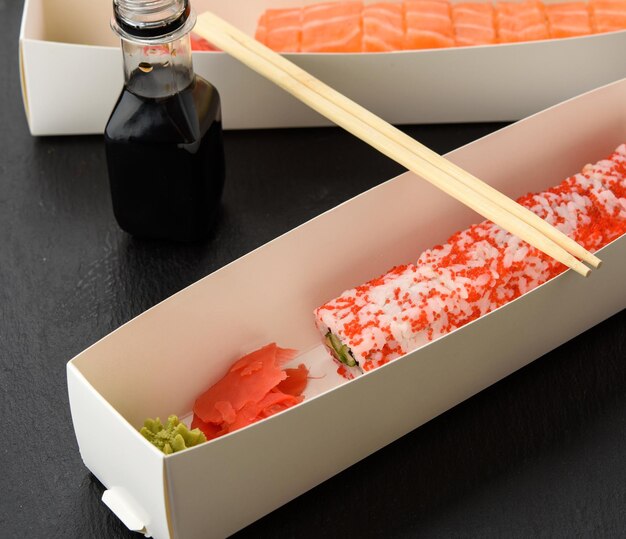 Foto kalifornisches sushi mit rotem tobiko-kaviar und scheiben philadelphia-sushi mit aal in einem weißen bo