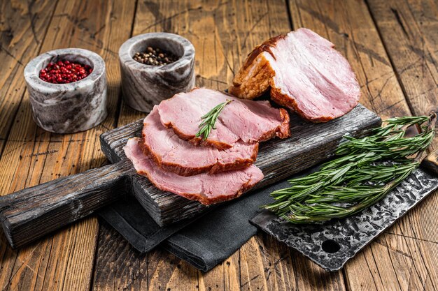 Kalt geräuchertes Schweinelendenfleisch mit Kräutern auf rustikalem Brett. Hölzerner Hintergrund. Ansicht von oben.