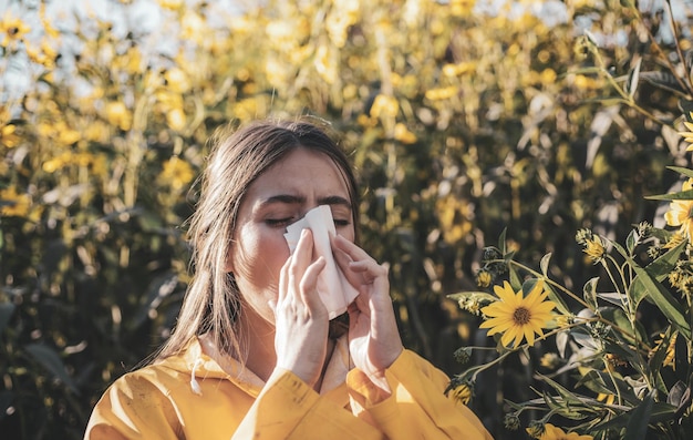 Kalte Grippesaison Schnupfen blühende Bäume im Hintergrund junges Mädchen niest und hält Papiergewebe
