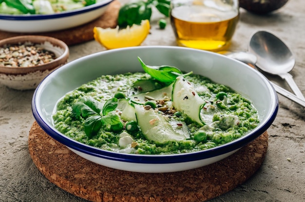 Kalte grüne Suppe Gazpacho mit Gurken, grünen Erbsen, Basilikumblättern und Avocado. Betonboden. Selektiver Fokus