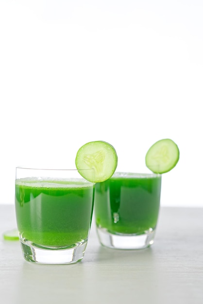 Kalte Gurkensuppe mit Avocado und Minze, Glas Gurkensaft auf grauem Holzhintergrund