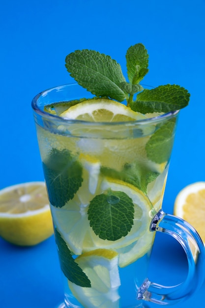 Kalte Limonade mit Zitrone und Minze im Glas auf blauem Hintergrund. Nahaufnahme.