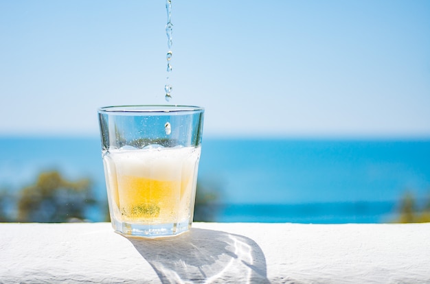 Kalte Limonade wird in ein Glas gegossen. Ein Glas erfrischende Limonade vor dem Hintergrund o