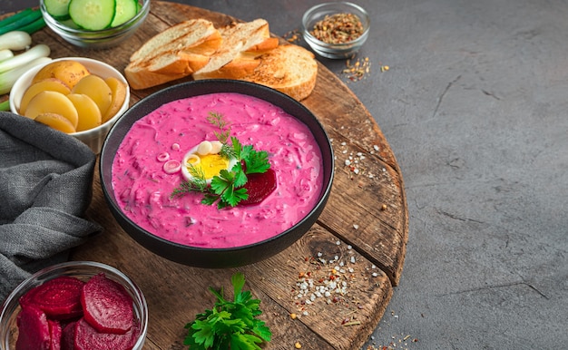 Kalte Rote-Bete-Suppe mit frischen Kräutern, Ei, Kartoffeln und Kefir. Ein traditionelles litauisches Gericht. Seitenansicht, Platz zum Kopieren.