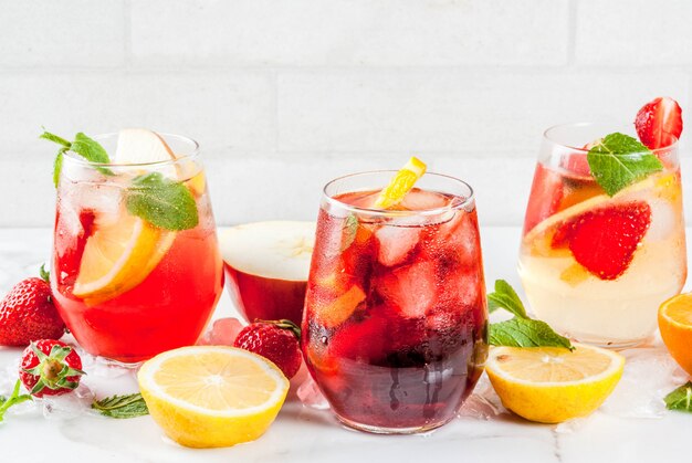 Kalte weiße rosa und rote Sangriacocktails mit Beeren und Minze der frischen Früchte.