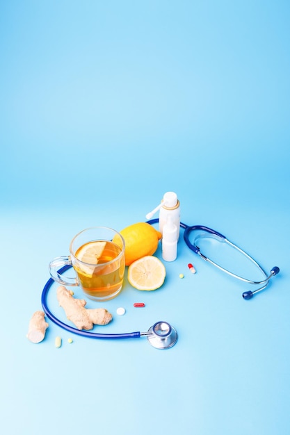 Kalte Zubereitungen Stethoskop Tee Zitrone und Ingwerwurzel auf blauem Hintergrund