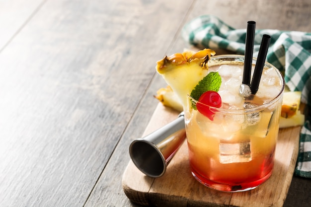 Kalter Cocktail mit Ananas und Kirsche auf Holztisch